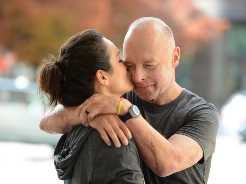 Two people hugging and getting a kiss on the cheek. 